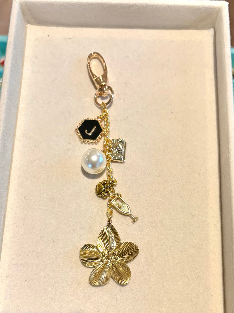 Gold flower-shaped pendant in a display box with a blurred background of jewelry.